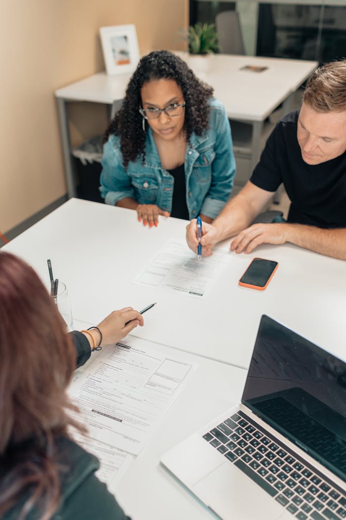 A couple discusses adoption papers with a professional in an office environment.